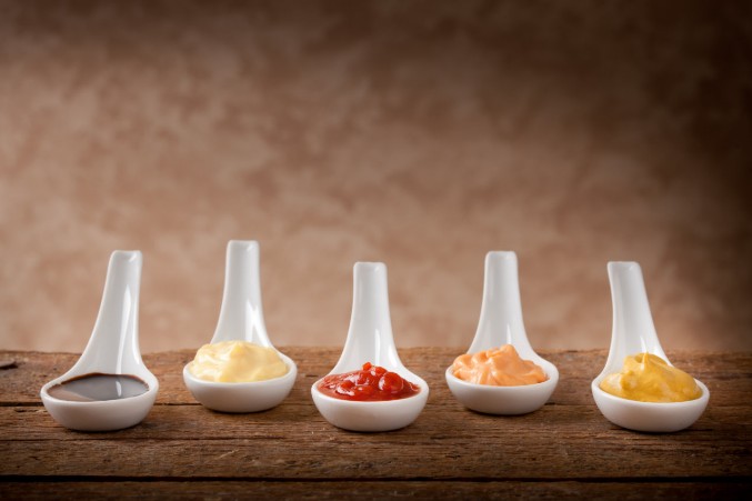 Raclette Saucen und Dips mehrere weisse Löffel mit verschiedenen Saucen und Dips gefüllt