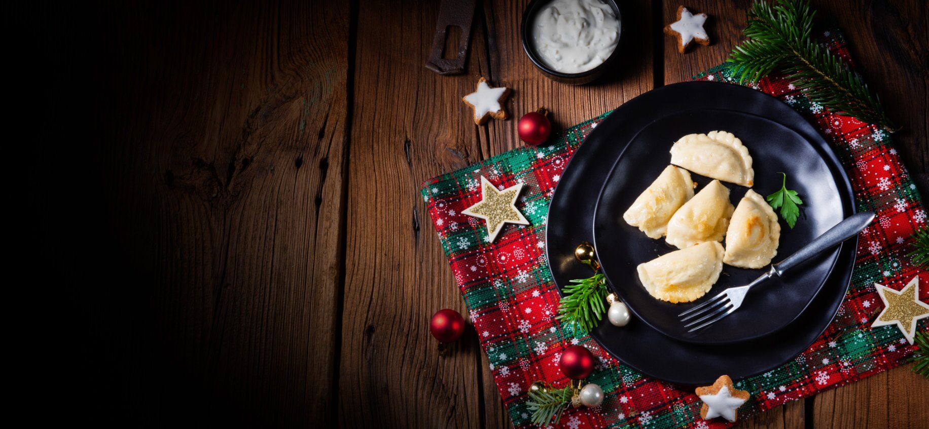 Vegetarische Steinpilzmaultaschen Ein schwarz Teller mit vegetarischen Steinpilzmaultaschen steht auf einen weihnachtlich dekorierten Tisch.